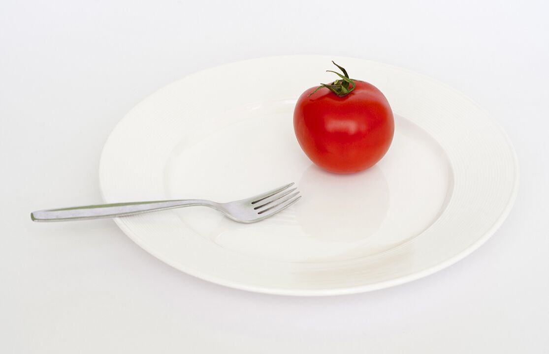помідор з вилкою на тарілці
